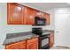 Kitchen featuring granite countertops, wood cabinets, and modern black appliances at 17474 W Acapulco Ln, Surprise, AZ 85388