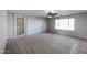 Spacious living room featuring neutral walls, carpet, ceiling fan, and natural light from a large window at 17474 W Acapulco Ln, Surprise, AZ 85388