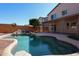 Backyard pool with rock waterfall feature, covered patio, and lush landscaping at 17474 W Acapulco Ln, Surprise, AZ 85388