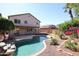 Backyard pool with rock accents and surrounding trees and greenery, partial view of home exterior at 17474 W Acapulco Ln, Surprise, AZ 85388