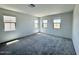 Bright bedroom featuring neutral carpeting, three windows, and white walls at 26029 N 23Rd Ave, Phoenix, AZ 85085