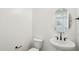 Powder room featuring a pedestal sink, round mirror, and wood-look flooring at 26029 N 23Rd Ave, Phoenix, AZ 85085