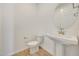 Modern powder room featuring a pedestal sink, round mirror, and wood-look tile flooring at 28958 N 174Th Ln, Surprise, AZ 85387