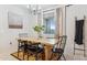 Modern dining room with a wooden table, black chairs, and neutral curtains with natural light at 5428 N 188Th Ln, Litchfield Park, AZ 85340