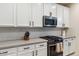 Kitchen with stainless steel microwave and oven, light countertops and backsplash, and white cabinetry at 5428 N 188Th Ln, Litchfield Park, AZ 85340