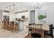 Open kitchen and dining area with stainless steel appliances, white cabinets, island seating, and modern chandelier at 5428 N 188Th Ln, Litchfield Park, AZ 85340