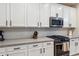 Close up of Kitchen with stainless steel microwave and oven, light countertops and backsplash, and white cabinetry at 5428 N 188Th Ln, Litchfield Park, AZ 85340