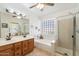 Bathroom featuring double sinks, a soaking tub with glass block window and glass enclosed shower at 5439 N Ormondo Way, Litchfield Park, AZ 85340