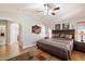 Inviting bedroom features a ceiling fan, wood floors and an arched entry to the en suite bathroom at 5439 N Ormondo Way, Litchfield Park, AZ 85340