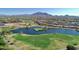 Stunning aerial view of a golf course community featuring a lake and mountain backdrop at 6271 S Twilight Ct, Gilbert, AZ 85298