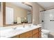 Bathroom featuring double sinks with granite countertop and a shower with white tile at 7810 W Wescott Dr, Glendale, AZ 85308