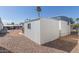 Side view of a white home and separate storage unit, with a small window and gravel yard at 9501 E Broadway Rd # 241, Mesa, AZ 85208