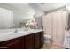 This bathroom features a large vanity, a neutral colored shower curtain, and tan-colored tile flooring at 10816 W Nosean Rd, Peoria, AZ 85383