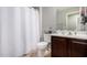 This bathroom features a shower-tub combo with a white shower curtain, dark wood vanity and beige tile floors at 10816 W Nosean Rd, Peoria, AZ 85383