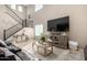 Bright living room featuring a large TV, stylish furniture, and a staircase leading to the upper level at 10816 W Nosean Rd, Peoria, AZ 85383