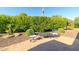 Backyard patio with seating and desert landscaping surrounded by green hedges at 13070 W Eagle Talon Trl, Peoria, AZ 85383