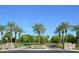 View of neighborhood entrance signs, palm trees, and green landscaping at 13070 W Eagle Talon Trl, Peoria, AZ 85383