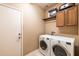 Laundry room with modern washer and dryer, built-in cabinets, and a convenient exterior access door at 13070 W Eagle Talon Trl, Peoria, AZ 85383