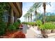 Beautiful walkway with manicured plants, palm trees, and a stone building exterior at 13070 W Eagle Talon Trl, Peoria, AZ 85383