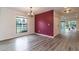 Open dining area with sleek gray flooring and a maroon accent wall, lit by a modern chandelier at 1327 W Glendale Ave, Phoenix, AZ 85021