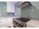 Close up view of stainless steel stove and hood with light blue backsplash and white cabinetry at 1327 W Glendale Ave, Phoenix, AZ 85021