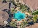 Aerial view of a community pool featuring multiple lounge chairs, palm trees, shade structures, and buildings at 14250 W Wigwam Blvd # 1022, Litchfield Park, AZ 85340