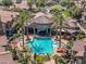 Aerial view of community pool surrounded by lounge chairs, a hot tub, palm trees, and shaded tables at 14250 W Wigwam Blvd # 1022, Litchfield Park, AZ 85340