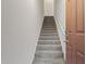 Carpeted staircase with a white handrail, leading upwards next to a solid wood door at 14250 W Wigwam Blvd # 1022, Litchfield Park, AZ 85340