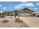 Charming stone home featuring desert landscaping, a spacious driveway, and a two-car garage under a sunny sky at 14458 W Powderhorn Dr, Surprise, AZ 85374