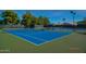 Bright blue tennis court with new nets surrounded by mature shade trees under a clear sunny sky at 14458 W Powderhorn Dr, Surprise, AZ 85374