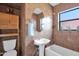 Cozy bathroom featuring a pedestal sink, tub, and tiled walls with a window for natural light at 1454 E Flower St, Phoenix, AZ 85014