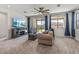 Bright living room with plush carpet, sliding glass doors with blue curtains, and a ceiling fan at 1627 E Walter Dr, Casa Grande, AZ 85122