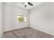 Simple bedroom featuring neutral carpet, walls, ceiling fan, and a window for plenty of natural light at 17125 W Saguaro Ln, Surprise, AZ 85388