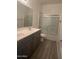 A well-lit bathroom featuring a double sink vanity, gray cabinets, and a shower with a sliding glass door at 1717 W Pollack St, Phoenix, AZ 85041