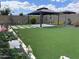 Expansive backyard with artificial turf, a gazebo, and flower gardens, creating a serene outdoor space at 19864 W San Juan Ave, Litchfield Park, AZ 85340