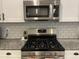 Stainless steel microwave and gas stove with white backsplash and granite countertops at 19864 W San Juan Ave, Litchfield Park, AZ 85340