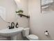 Stylish powder room featuring a pedestal sink, round mirror, and decorative shelf with a plant and candle at 2116 S Moccasin Trl, Gilbert, AZ 85295