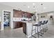 A kitchen island with barstool seating beneath pendant lighting, stainless appliances, and a pantry at 22800 E Via Las Brisas Rd, Queen Creek, AZ 85142