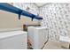 Well-organized laundry room with floral wallpaper, blue shelving, and modern washer and dryer appliances at 22800 E Via Las Brisas Rd, Queen Creek, AZ 85142