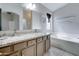 Bathroom with double sinks, a large mirror, granite counters, and a soaking tub at 2501 N 114Th Ave, Avondale, AZ 85392