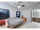 A bright bedroom features a ceiling fan, patterned bedding, and an adjacent bathroom at 2501 N 114Th Ave, Avondale, AZ 85392