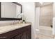 Well lit bathroom featuring a tiled shower/tub, a dark vanity, granite countertops and a decorative flower at 2537 N Miller Rd, Scottsdale, AZ 85257