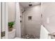 Modern shower features white tiling, a shower head with faucet, and decorative rocks on the floor at 2537 N Miller Rd, Scottsdale, AZ 85257