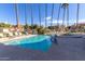 A community pool and spa surrounded by lounge chairs and palm trees at 30 E Brown Rd # 2052, Mesa, AZ 85201