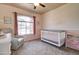 A cozy Bedroom featuring soft peach walls, a white crib, a recliner, and a bright window at 3542 E Pala Ct, Gilbert, AZ 85297