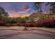 Exterior shot of a stone fountain with flowering desert plants and colorful sunset skies in the background at 5254 E Arroyo Rd, Paradise Valley, AZ 85253