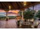 Outdoor patio with a fireplace, seating area, lush greenery, and a view of the setting sun at 5254 E Arroyo Rd, Paradise Valley, AZ 85253