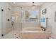 Soaking tub and glass shower with natural light, luxury finishes, and modern design at 5779 S Penrose Dr, Gilbert, AZ 85298