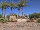 Elegant Freeman Farms entrance sign framed by towering palm trees, vibrant flowers, and stone architecture at 5779 S Penrose Dr, Gilbert, AZ 85298