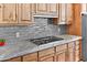 Close-up of a gas cooktop and marble countertops with gray tile backsplash, and wooden cabinetry at 8154 E Tecolote Cir, Scottsdale, AZ 85266